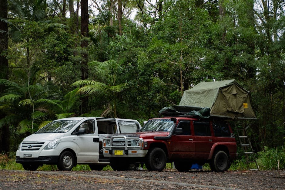 Two SUVs with camping gear in a lush forest, ideal for travel and adventure enthusiasts.